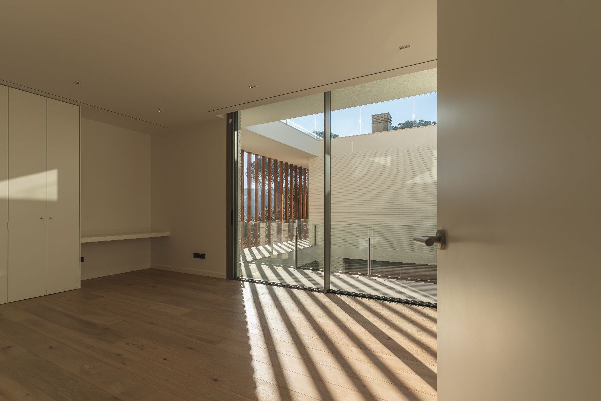 Minimalist room with large sliding glass doors leading to a balcony and letting natural light into the space