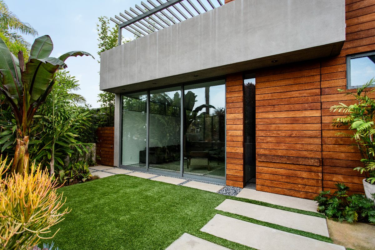 Contemporary home exterior with aluminium sliding glass doors, wood cladding, and landscaped garden