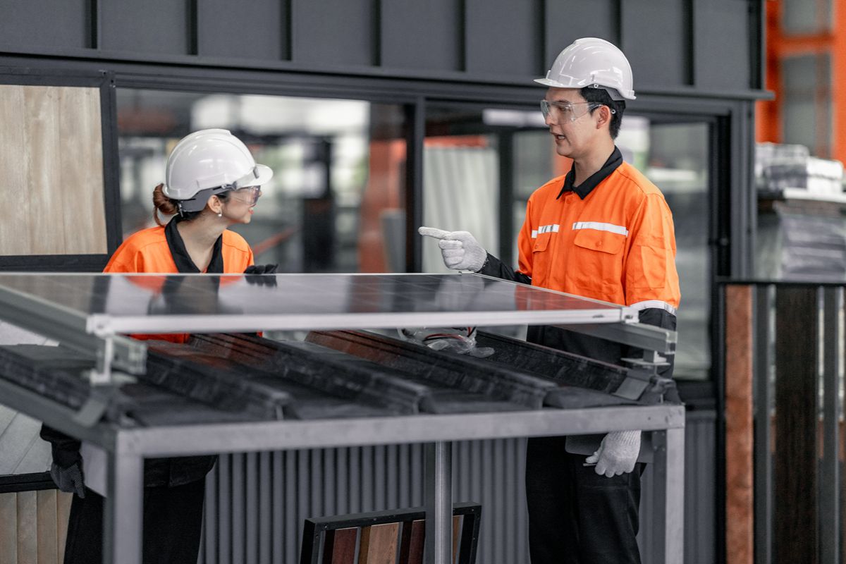 Factory workers discussing aluminum door components during a quality control inspection