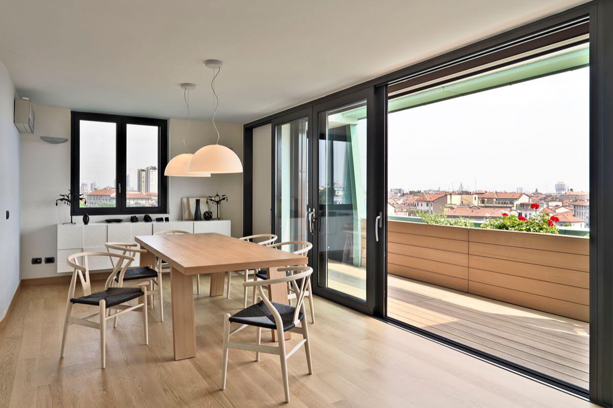 Modern dining area with black aluminum sliding doors leading to a balcony