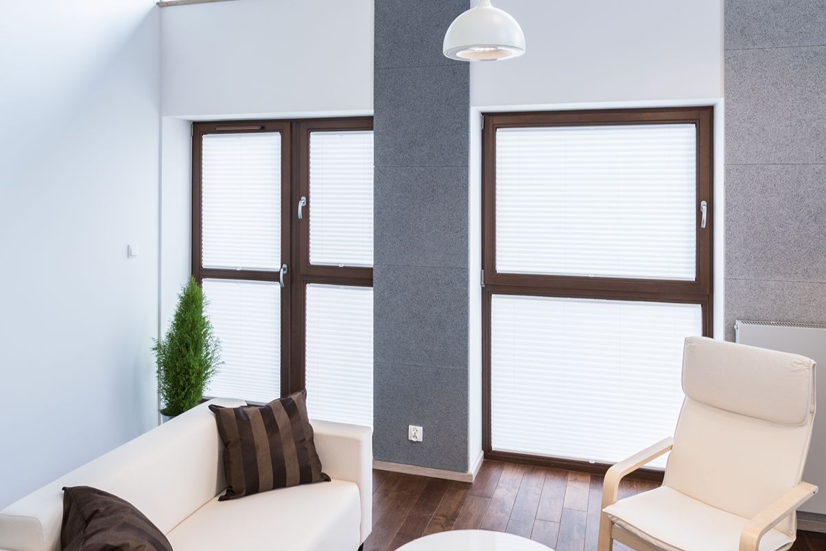 Bright living area with brown-framed awning windows and blinds for privacy and ventilation