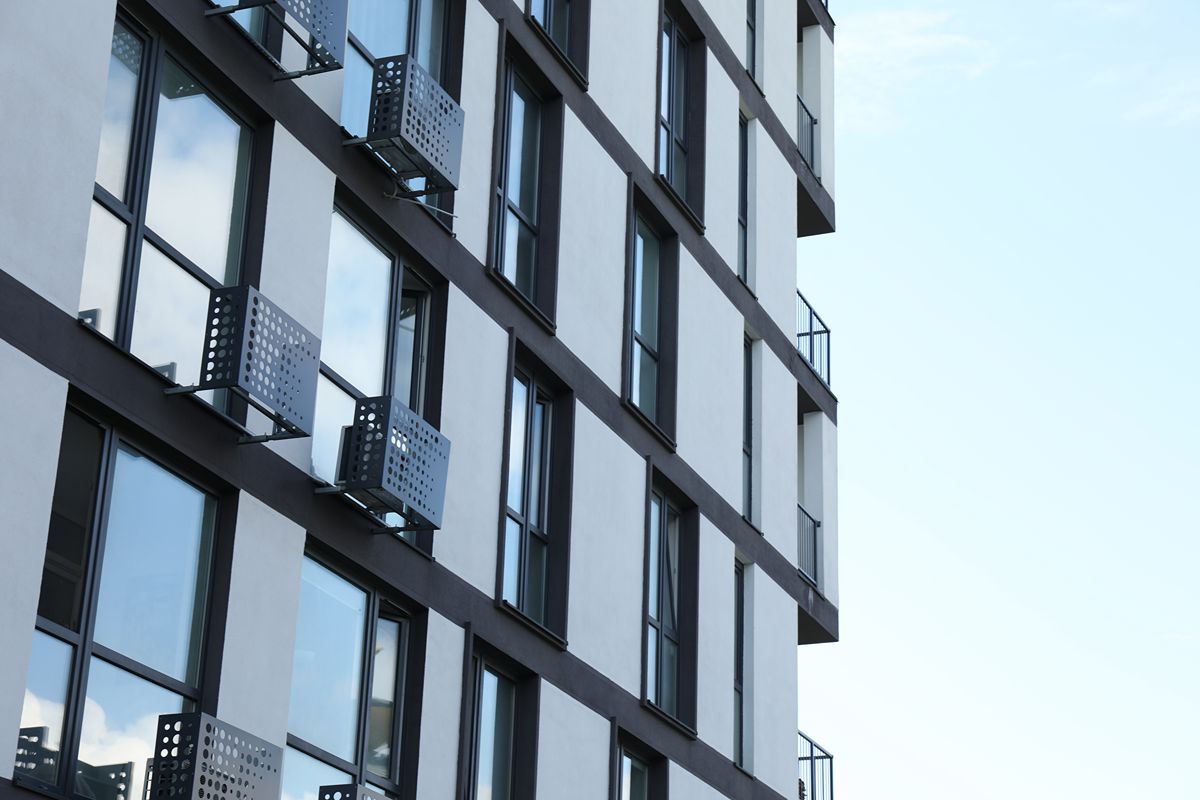 Exterior of a modern hotel building featuring large glass windows with dark aluminum frames and reflective glazing