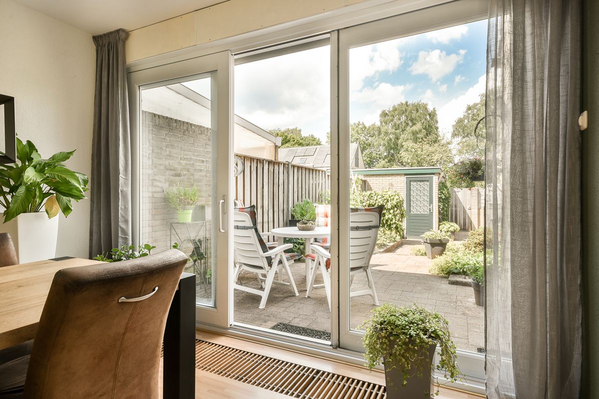 Floor-to-ceiling aluminum sliding glass doors connecting a modern interior to a balcony with outdoor views