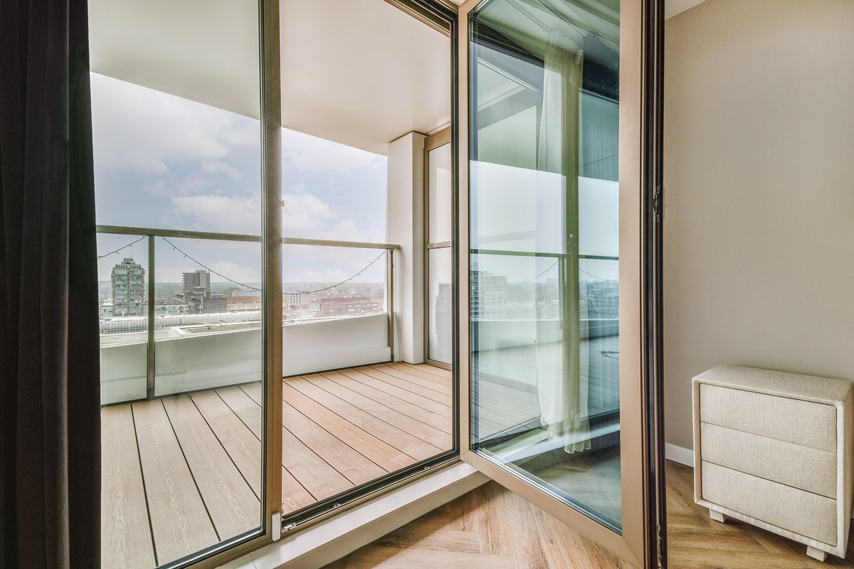 White aluminum-framed sliding glass doors opening from a bright living area to a landscaped patio with outdoor furniture
